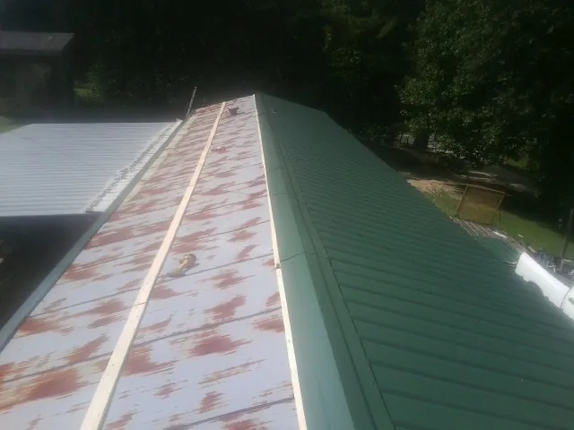 Old rusted panels beside newly installed green metal roofing — Wind Damage Roof Repair by Roofing Brothers in Newnan
