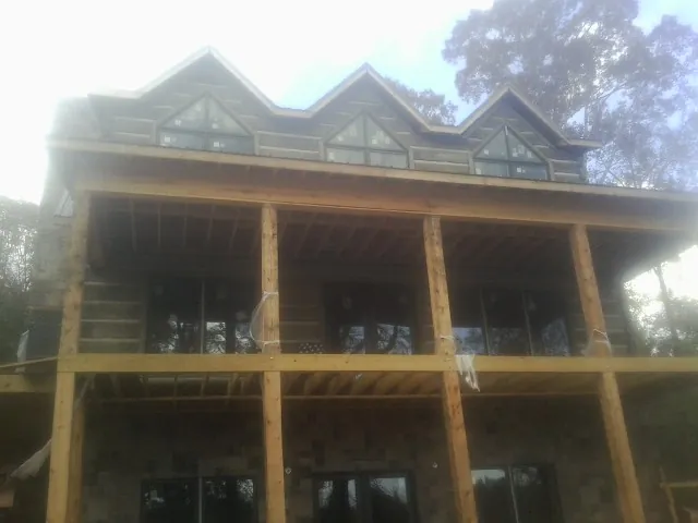 Dormers and porch framing on a large log home under construction — Roof Coating work by our crew in Newnan