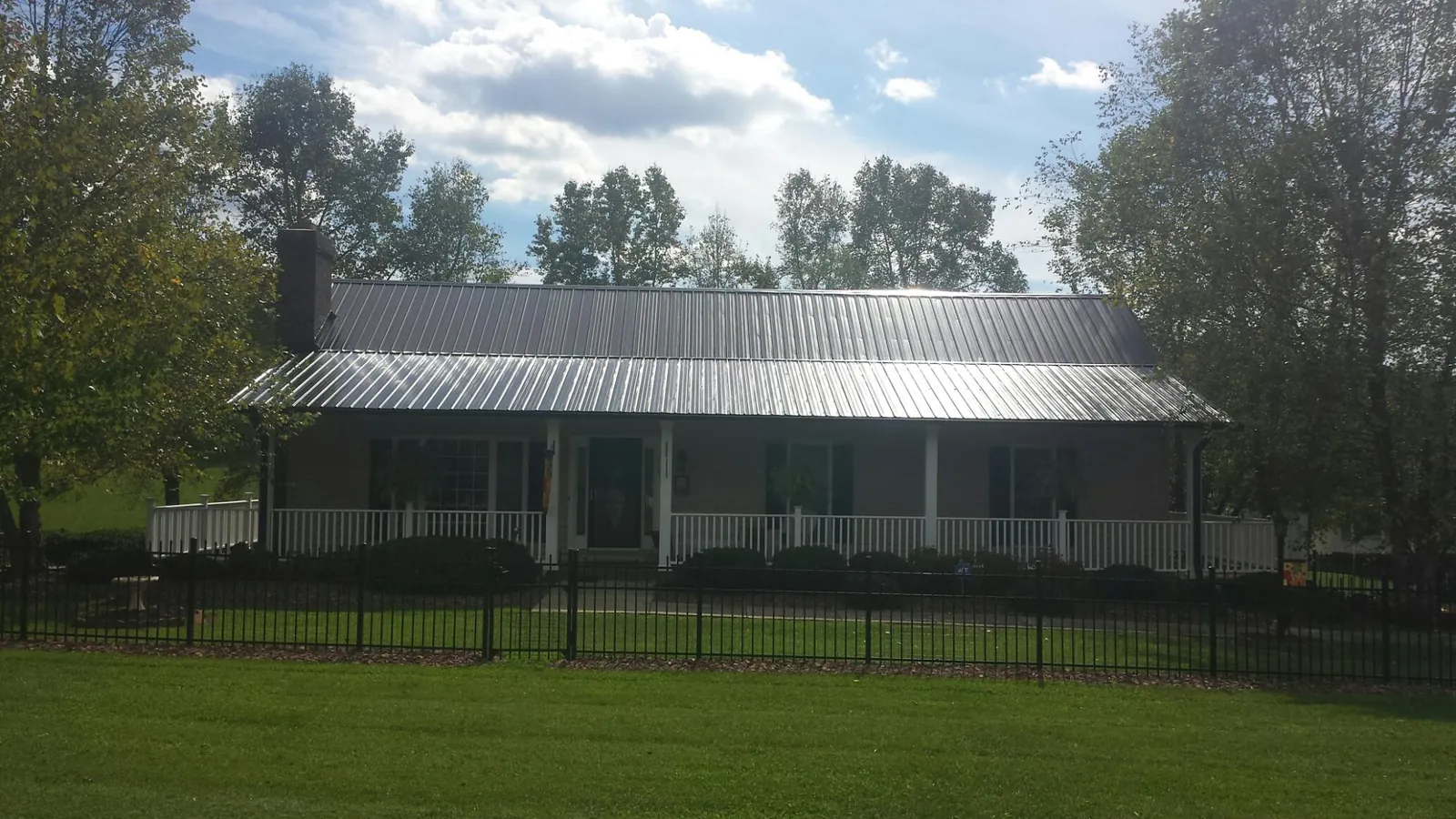 Gray metal roof on a brick ranch with a full width front porch — Gutter Guard Installation work by our crew in Newnan