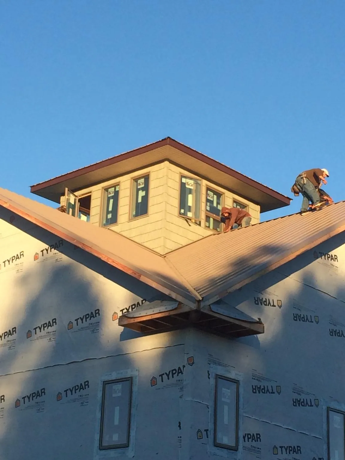 Roofers working around a rooftop cupola on a new metal roof at sunset — Roof Waterproofing in Newnan by Roofing Brothers